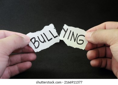 Fight and stop bullying concept. Hand tearing paper with word bullying in dark black background. - Powered by Shutterstock