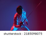 Fight in swordplay. Male fencer with smallsword practicing fencing isolated on purple background in neon light. Athlete practicing in motion, action. Copyspace for ad.