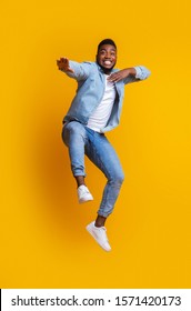 Fight with your diffidence. Funny african american guy jumping and making karate moves on yellow background with free space