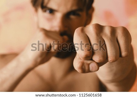 Fighter with defocused face practices boxing. Mans fist on colorful background, close up.