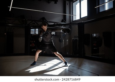Fighter immersed in shadowboxing in rays of sunlight in boxing gym