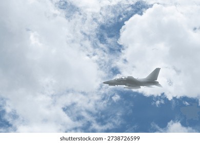 Fighter jet flying through cloudy blue sky on background with copy space