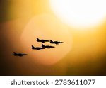Fighter jets flying in precise formation across a vibrant sunset sky
