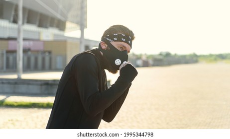 Fighter man training boxing punch on urban street. Portrait of fitness man boxing outdoor at black respirator. - Powered by Shutterstock