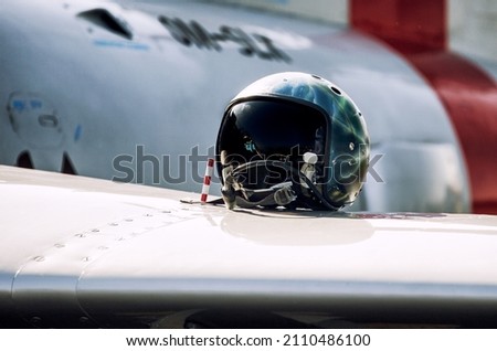 Fighter pilot helmet with visor and oxygen mask placed on wing of military jet, symbolizing high-tech aviation, air combat readiness and modern air force power.