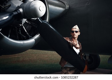 Fighter Pilot With Sunglasses In Full Flight Gear Standing At The Front Of His Jet