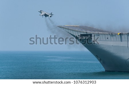 A fighter plane during a vertical take-off from an aircraft carrier at sea. A spanish navy combat plane during a war operation at sea