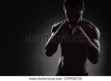 Fighter silhouette. Handsome athletic man in boxing stand on a dark background