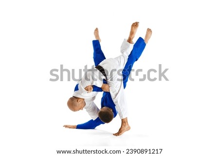 Fighting judokas, two professional combat sportsmen, performing their skills while competition isolated white studio background. Concept of martial art, health, strength, energy, fit. Copy space, ad.