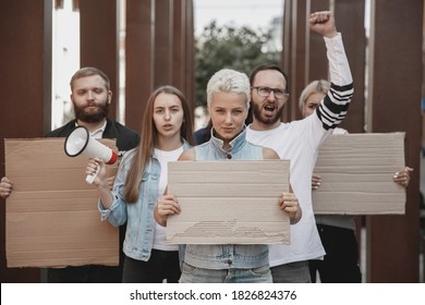 Fighting for more. Group of activists giving slogans in a rally. Caucasian men and women marching together in a protest in the city. Look angry, hopeful, confident. Blank banners for your design or ad - Powered by Shutterstock