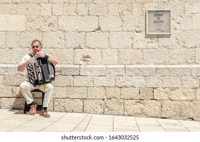 Figueres, Spain, 05/05/2019 A Street Busker Entertainer With A Vintage Antique Accordion Taking A Break And Drinking Some Water In The Intense Summer Heat. European Music Busker.