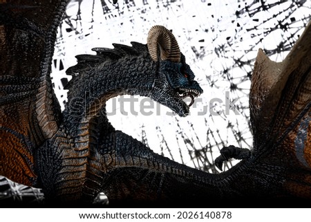The figure of a fabulous gloomy dragon with raised wings and a curved neck in a defense pose against a gray shabby background