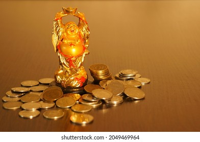 Figure of the Golden Buddha on the table. Next to it is a stack of coins. Symbol of wealth and prosperity.