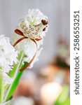 
A figure of a hen on a stick among a bouquet of white hyacinths. Easter symbol, postcard motif.