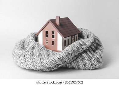 Figure of house and warm scarf on light background. Concept of heating season