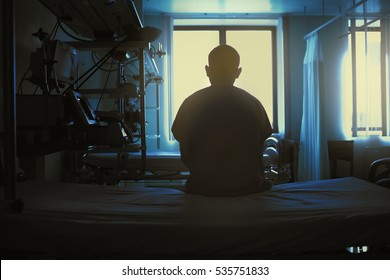 Figure of sitting patient on a hospital bed on the background of bright lights - Powered by Shutterstock