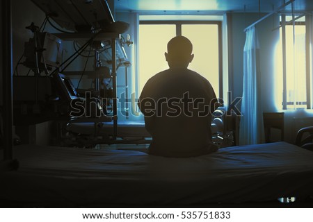 Figure of sitting patient on a hospital bed on the background of bright lights