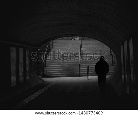 Figure walking through dark underpass