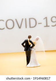 Figure Of A Wedding Couple Standing In Front Of A Large Lettering With Covid 19 And Celebrating Alone Without Party Guests. Vertical