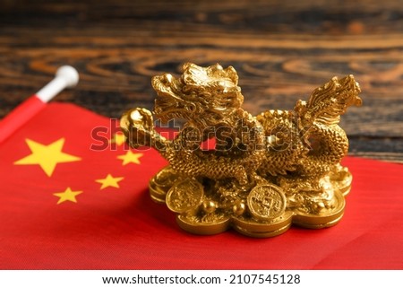 Figurine of dragon and Chinese flag on wooden background