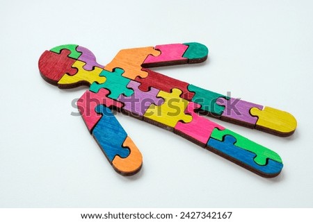 A figurine of man made from colored puzzle pieces. Unity or neurodiversity concept.