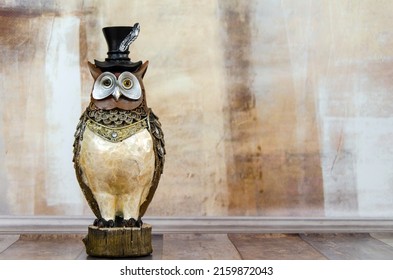 figurine of an owl on the background of a textured wall. A figurine of a solid business owl, a symbol of wisdom, judicial law, obtaining knowledge. The concept of training, jurisprudence.
