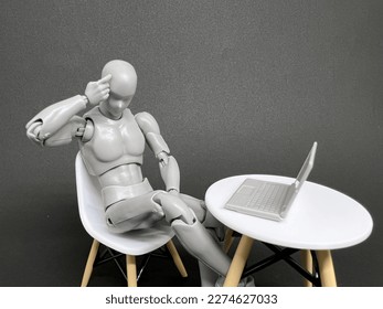 A figurine is struggling to make decision in front laptop 