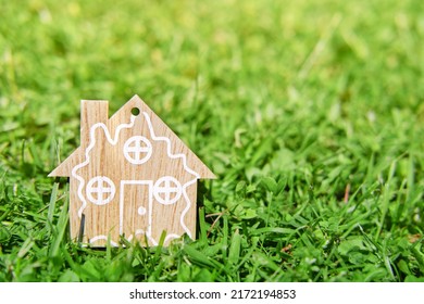 Figurine of wooden house on green grass. The concept of eco wooden house. Summer bright sunlight.