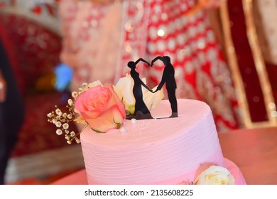 Figurines of the bride and groom on a wedding cake.Funny figurines suite at a luxury wedding white cake decorated .Figurines on top of wedding cake with roses decorations.