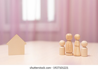 Figurines Of A Family Of 4 Next To A Wooden House
