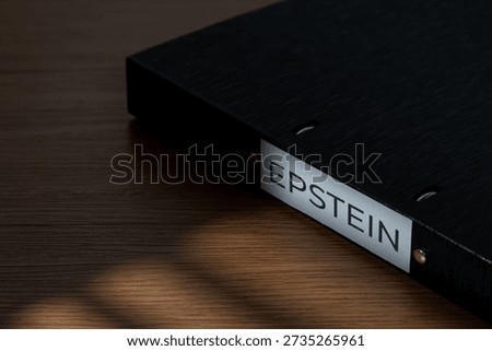 A file folder labeled EPSTEIN on a wooden desk. Investigations, court documents, hidden evidence, and public scandals related to high-profile legal cases concept.