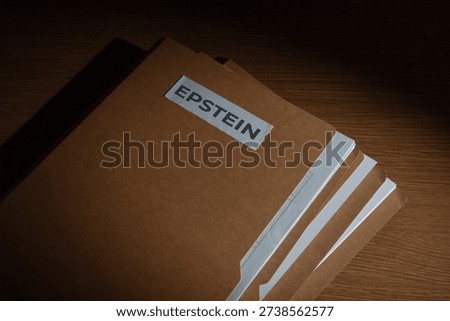 A file folder labeled EPSTEIN on a dark surface. Investigations, court documents, hidden evidence, and public scandals related to high-profile legal cases concept.