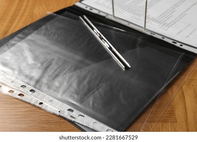 File folder with punched pockets on wooden table, closeup