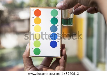 file of hand holding water ph testing test comparing color to indicated 