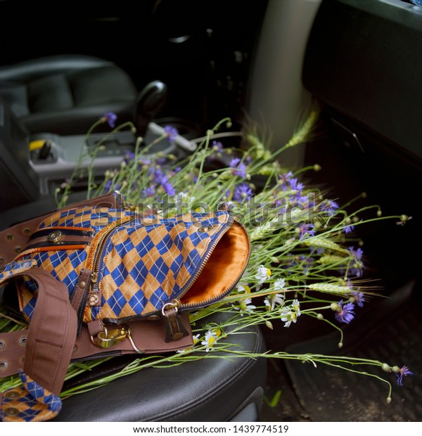 Filed\
flowers and lady handbag on the car front\
seat