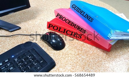 Files with label guidelines, procedures and policies on a table.