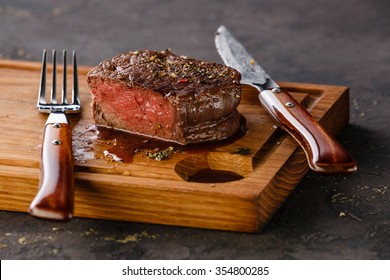 Filet Mignon Steak on wooden board on black background