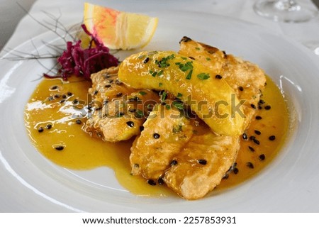 Filete de Espada with banana and passion fruit sauce. The black swordfish - the most typical fish on the island of Madeira. Typical madeiran dish Espada on white plate served with passion fruit sauce.