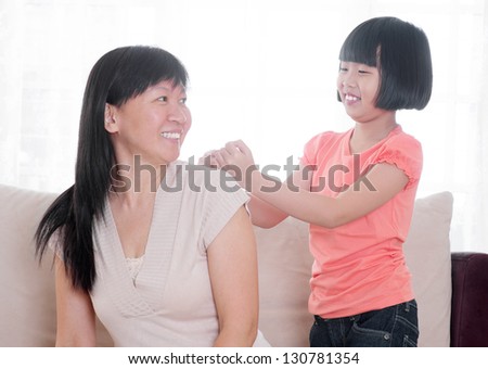 Filial piety concept. Southeast Asian child doing shoulder massage to her mother at home.