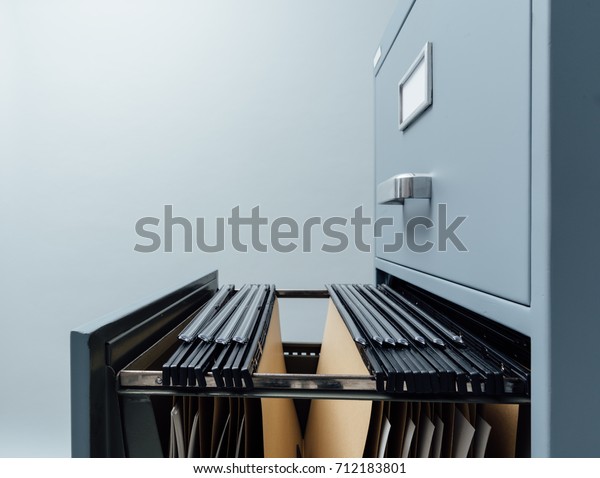 Filing cabinet with open drawer and files\
inside: data storage and\
archives