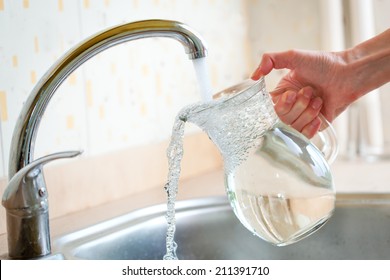Filing glass pitcher with water from tap