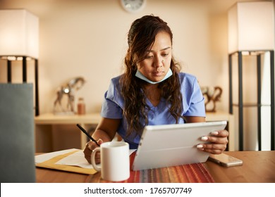 filipina nurse working from home doing paperwork and using tablet