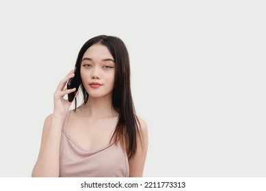 A Filipina Poses For The Camera For A Studio Shot Isolated On White Background While Talking On The Phone With Her Friends. Studio Shot Isolated On White Background.