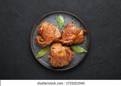 Filipino Chicken Adobo on dark gray plate on black slate backdrop. Chicken Adobo is Filipino cuisine dish of braised chicken thighs, soy sauce, vinegar, black pepper and bay leaves. Filipino food