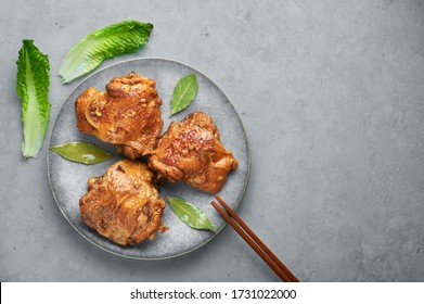 Filipino Chicken Adobo on gray plate on concrete backdrop. Chicken Adobo is Filipino cuisine dish of braised chicken thighs, soy sauce, vinegar, black pepper and bay leaves. Filipino food. Copy space