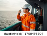 Filipino deck Officer on deck of vessel or ship , wearing PPE personal protective equipment. He holds VHF walkie-talkie radio in hands. Dream work at sea