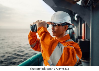 Filipino deck Officer on deck of vessel or ship , wearing PPE personal protective equipment. He is looking through binoculars.