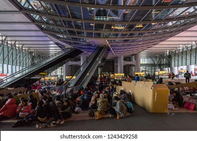 Filipino and Indonesian maids on their day off sitting in groups on the pavement of HSBC building atrium. Hong Kong, Central, January 2018