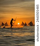 Filipino kid sailing the beautiful Boracay waters in front of boats during sunset.