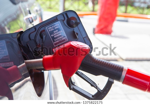 Fill the car with fuel. The car is filled with
gasoline at a gas station. Gas station pump. Man refueling gasoline
with fuel in a car, holding a nozzle. Limited depth of field.
Blurred image Close-up.